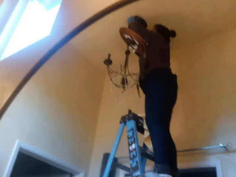 Electrician installing a chandelier in a Huntington Beach residence